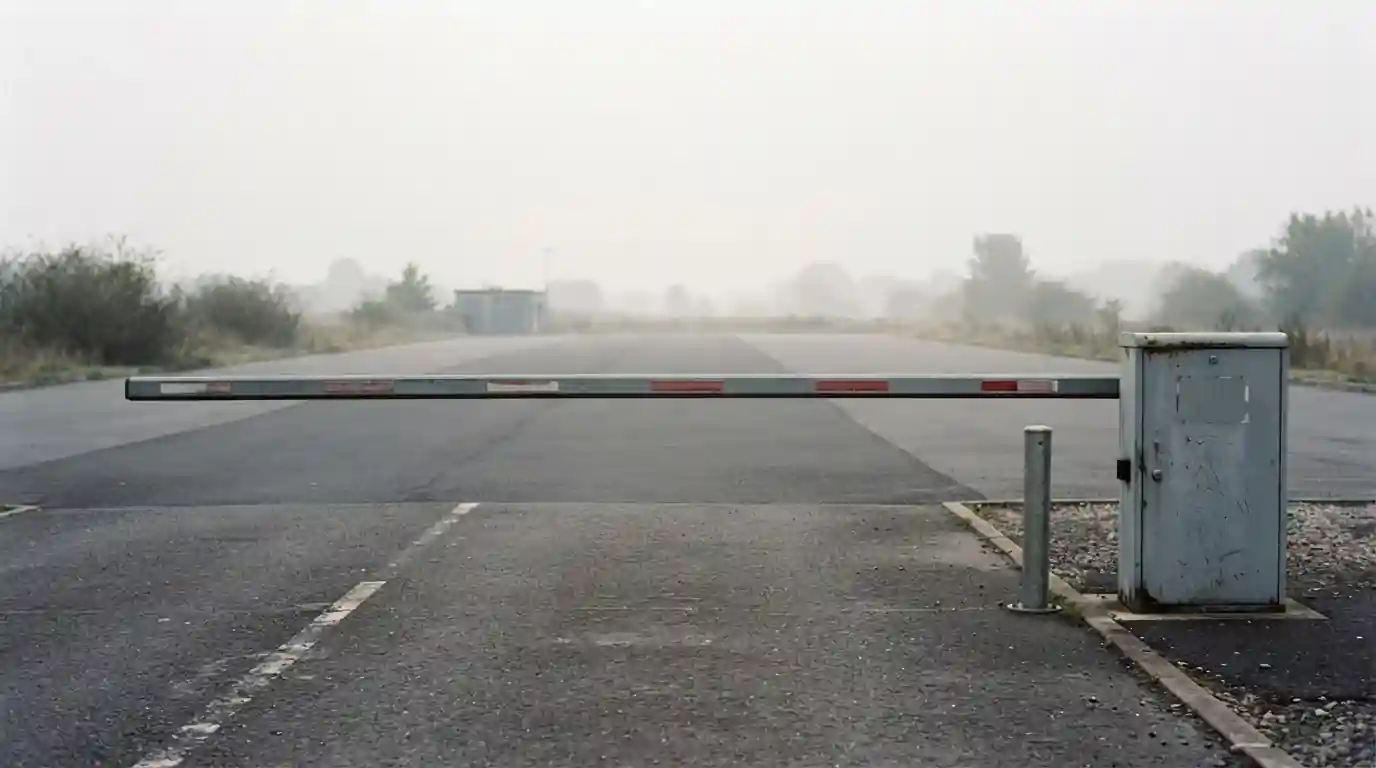 Schranke an einer Zufahrt, dahinter eine ruhige leere Fläche